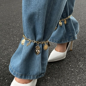 Gold chain anklet with cross and sacred heart charms styled with white heels and jeans