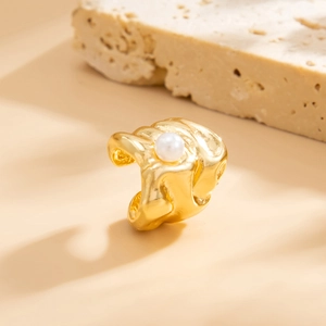 Macro-opname van goudkleurige ring met textuur en witte parel op natuurlijke steen