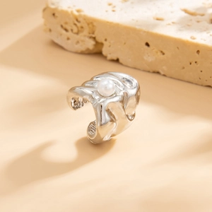 Detail van een zilveren ear cuff met vloeibaar metaal effect en witte parel op steen