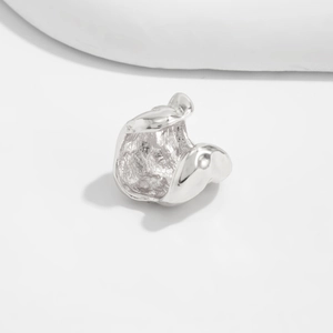 Detail van een zilveren organische lava-stijl oorbel met getextureerde metalen binnenkant