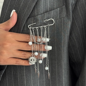 Silver safety pin brooch with star charms and tassels on a grey pinstripe suit jacket