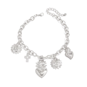 Dettaglio del bracciale a catena argento con pendenti a croce e cuore su sfondo bianco