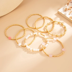 Vue détaillée du lot de bracelets dorés avec breloques croix et perles d'imitation