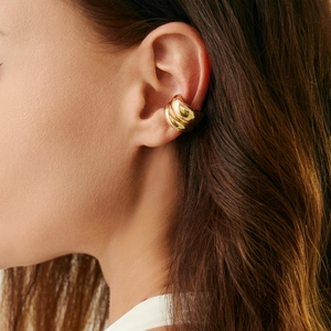 Detailopname van een gelaagde gouden ear cuff op het oorkraakbeen, minimalistisch sieraad