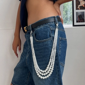 Three-layer white faux pearl waist chain with silver metal clasps on denim jeans
