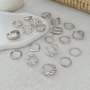 Détail macro de diverses bagues empilables en argent avec motifs de cœur et chaîne