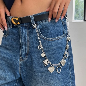 Chaîne de taille multicouche style punk argentée avec pendentifs cœur sur un jean