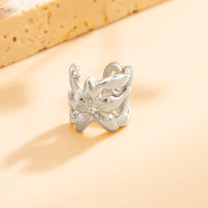 Detailopname van zilveren bloemen ear cuff met geplooide blaadjes en maritieme textuur