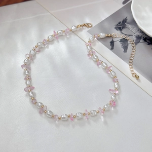 Detailopname van de boheemse kralenketting met witte parels en roze stenen op witte zijde