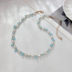 Detail van barokparels en blauwe stenen kralenketting met gouden karabijnsluiting