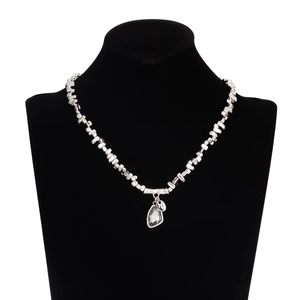 Detailed macro of silver irregular beads and teardrop crystal pendant on a black bust