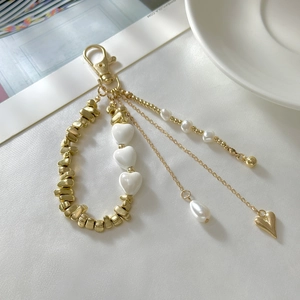 Detail view of multi-layer gold keychain with heart charms and white pearls