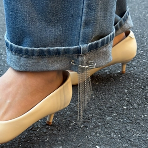 Nahaufnahme einer silbernen Stern-Quastenkette als Brosche an einer blauen Jeans