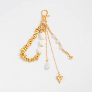 Close-up of golden keychain with ceramic hearts, irregular metal beads and white pearls