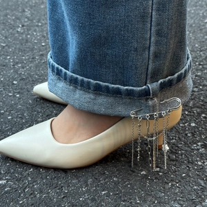 Spilla da balia in metallo argento con ciondoli a stella e lunghe nappe a catena sui jeans