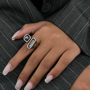 Détail de bague argentée avec deux pierres grises sur un mannequin en costume gris