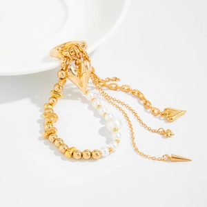 Detailed view of layered gold heart charms with white pearls and hanging chain tassels