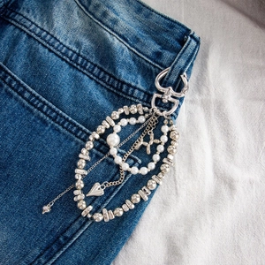 Detail of layered silver pants chain featuring a balloon dog charm and heart clasp