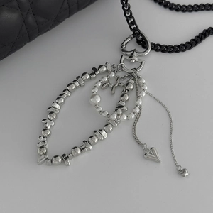 Detail showing heart charm with black curb chain and faux pearl accents on a bag charm