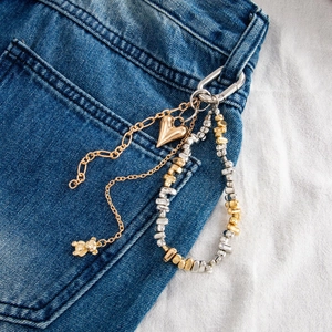 Close-up of multilayer heart and bear charms on a metallic chain for jeans