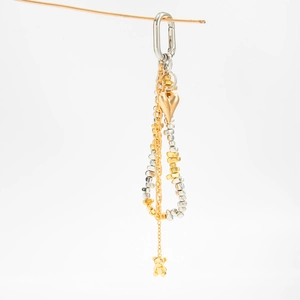 Detail of mixed metal heart and bear charms on a beaded bag chain with carabiner
