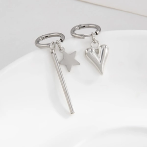 Asymmetric silver star and heart pendant drop earrings on white ceramic rim