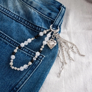 Detail of beaded trousers chain with silver heart pendant and star charms on jeans