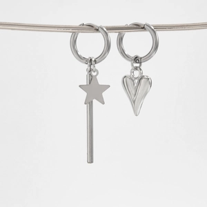 Detail of silver asymmetric earrings with star and heart charms on a sleek metal stand