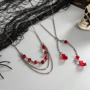 Collier gothique multicouche avec perles en cristal rouge et chaîne argentée sur blanc