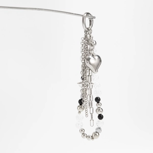 Detail of silver heart pendant chain with black beads and star charm on white background