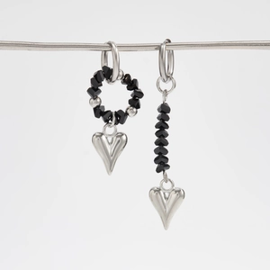 Detail of asymmetric silver earrings with black faceted beads and heart shaped pendants