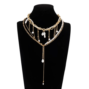 Dettaglio della collana a catene dorate sovrapposte con perle barocche su busto nero