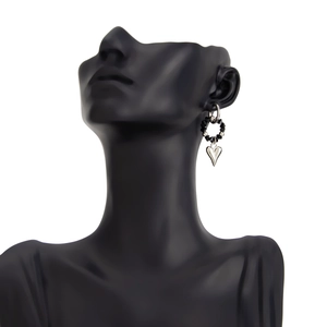 Detailed close-up of a silver heart-shaped pendant with black beaded accents on a mannequin