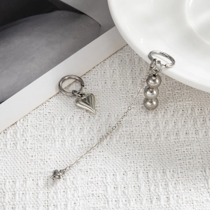Close-up of asymmetrical silver star and heart earrings with delicate chain tassels