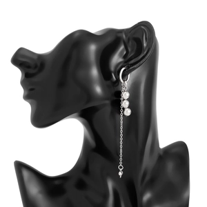 Detail view of long tassel earrings with beads and chain on a black display model