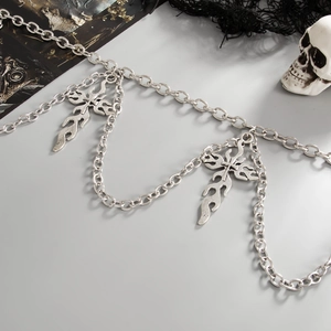 Gothic silver body chain with cross and flame pendants over black mesh background