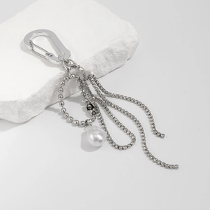 Silver chain keychain with large irregular pearl and sparkling rhinestone tassels on white stone