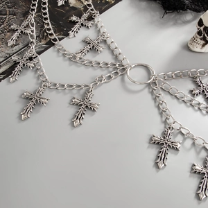 Detail of gothic silver cross tassels and layered metal chains on a body chain accessory