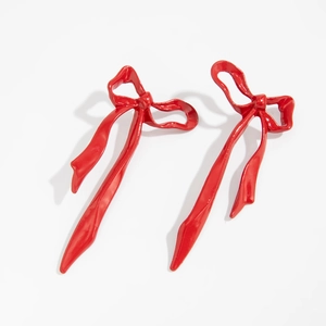 Macro view of metallic red bow earrings with high-gloss finish and detailed ribbon folds