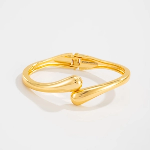 Detailed macro view of gold-plated waterdrop hinge bracelet with polished mirror finish