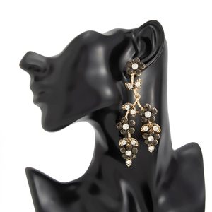 Détail de boucles d'oreilles pendantes dorées serties de cristaux noirs sur un mannequin