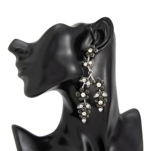 Détail de boucles d'oreilles à pampilles avec strass gris et motif de feuille rétro