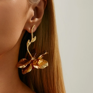 Nahaufnahme eines großen goldenen Blumenohrings mit texturierten Blüten und Blattdetails