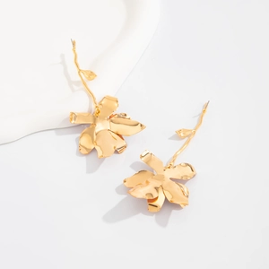 Detailed view of golden metal 3D flower earrings with long stems on a white surface