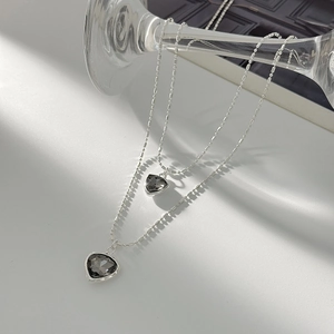 Close-up of double-layered silver chain with two dark grey heart crystal pendants