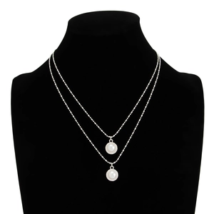 Detail of silver layered necklace with faux pearl pendants on a black velvet display stand