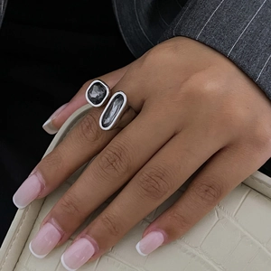 Détail d'une bague double pierre argentée avec gemmes grises portée avec un blazer gris