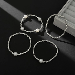 Detailed view of silver metal bead rings with white pearls on a dark textured surface