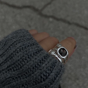 Détail d'une bague géométrique argentée avec pierre grise sur fond de pull en maille