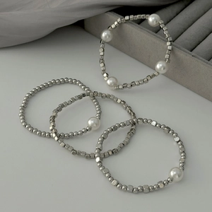 Close-up of four-piece beaded bracelet set with silver metal and white pearls